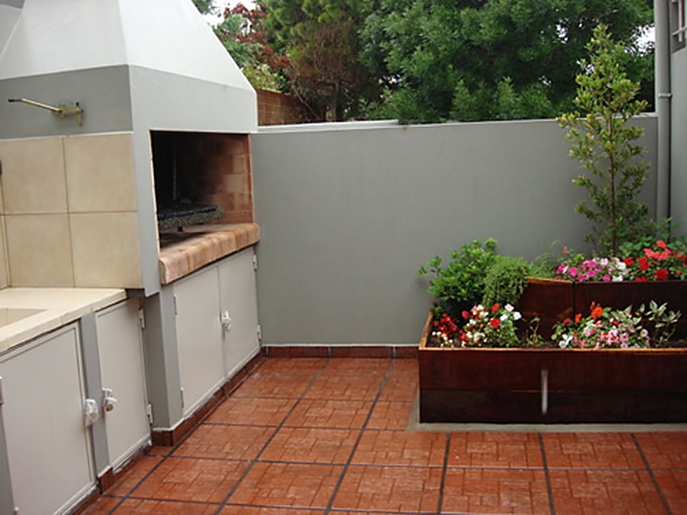 Patio con parrilla y canteros con flores